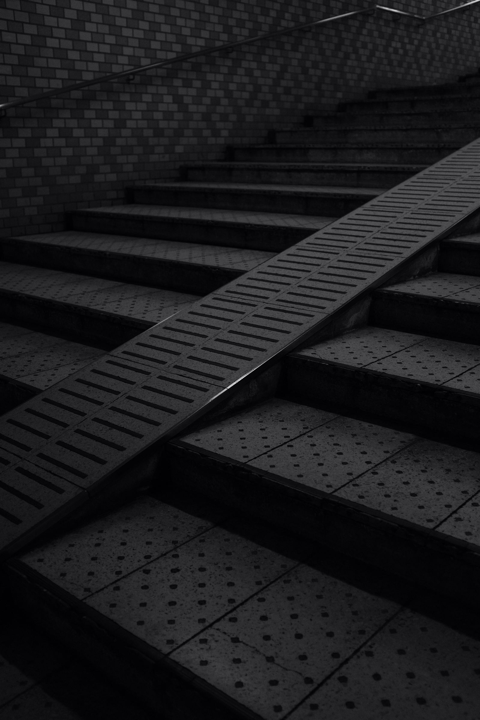 A diagonal shaft of light crossing a dark concrete ramp, evoking a depot loading bay at dawn.